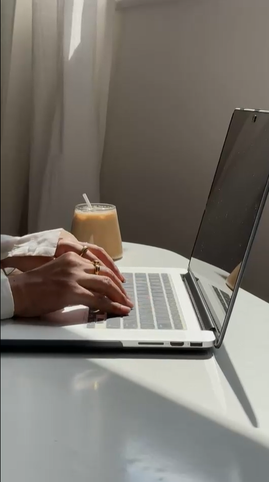 Aesthetic workspace with iced coffee and laptop in sunlight