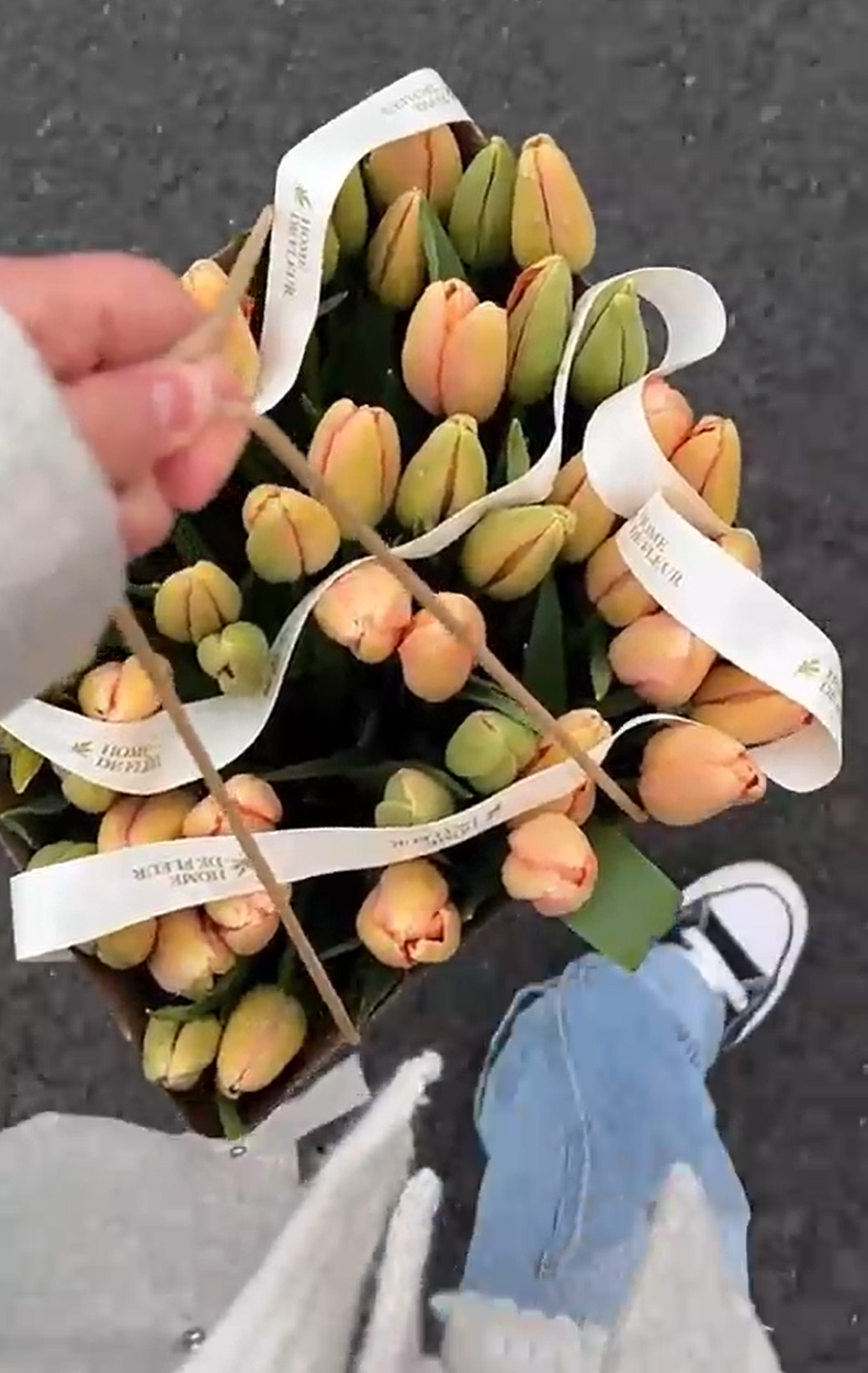 Strolling with a bouquet of orange tulips tied with white ribbons