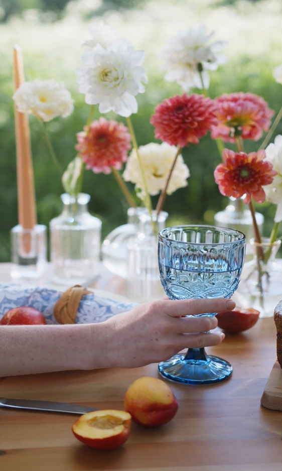 glass of water with fruit and flowers background on wooden bench