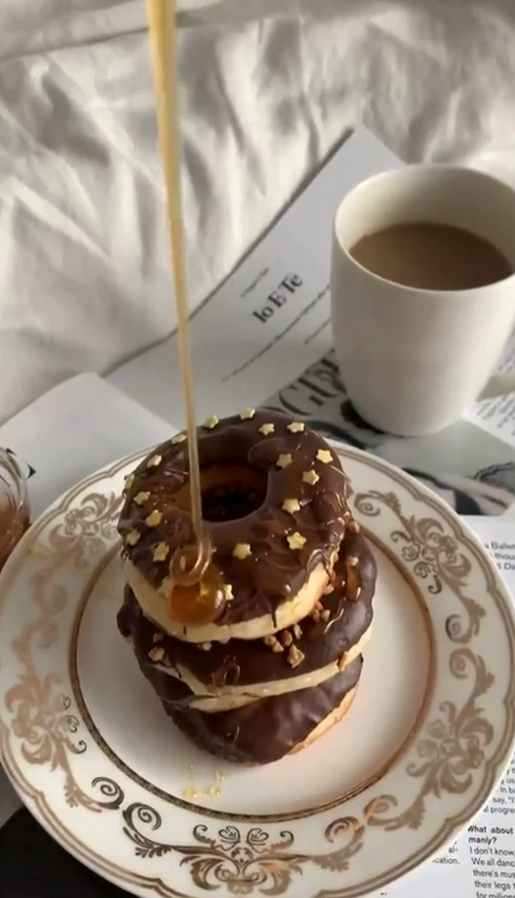 honey pouring onto chocolate donuts with coffee and magazine